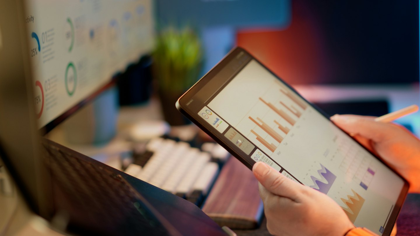 Persona analizando gráficos de negocios en una tableta en un escritorio.